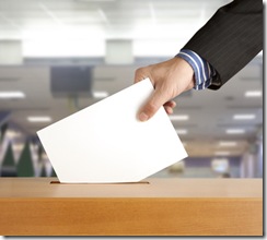 Hand putting a voting ballot in a slot of box 